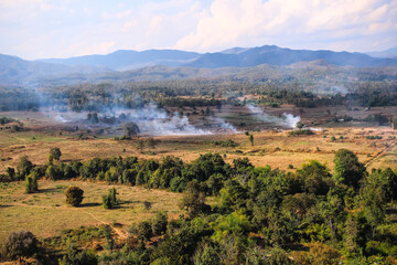 Fototapeta na wymiar Smoke from burning at rice farm for agriculture on mountains view landscape and blue sky background in Chiang Mai , Thailand