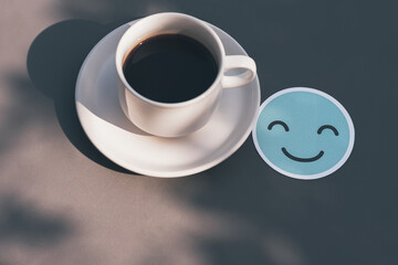 Smile face paper cut and White coffee cup on gray table There is space on the side for design or product placement, Relaxing and refresh concept.