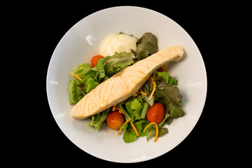 Die cut of Salmon serve with vegetable salad on black isolated.