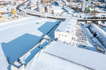 Fototapeta na wymiar snow-covered industrial area with warehouses and manufacturing buildings. aerial view in winter sunny day.