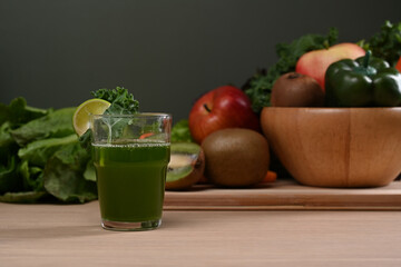 Green smoothie in glass and fresh green vegetables on wooden table. Healthy food concept.