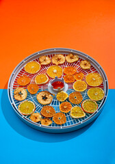 Dried apples, lemon and orange on the frame for drying on a colored background