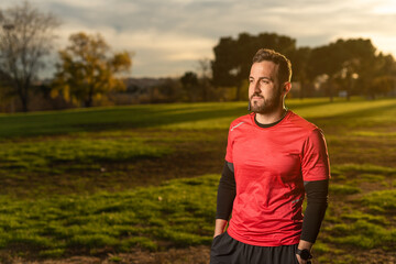 Confident athlete listening to music in park at sunset