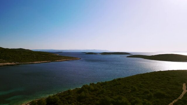 Drone shot of a beach on a tropical island with sea and small islands on the horizon with clear sky. Beautiful Mediterranean environment a famous tourist destination. Rukavac, Island Vis, Croatia 4K