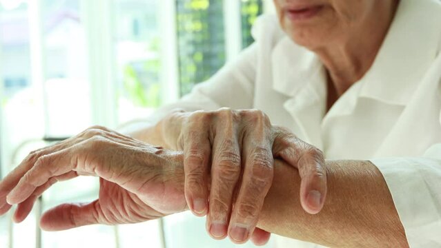 Old elderly massaging her wrist,injury,bone pain in wrist,numbness or beriberi,asian senior woman suffering from De quervain's disease,weakness in hand,concept of arthritis,arthritic nerve,tendonitis