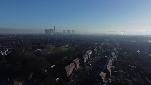 Misty English town houses under power station smokestack skyline aerial rising view above neighbourhood