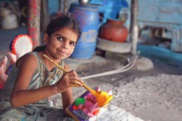 Indian little girl painting the god doll for festival