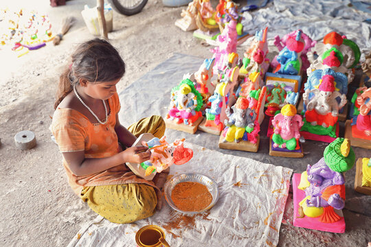 Indian little girl painting the god doll for festival