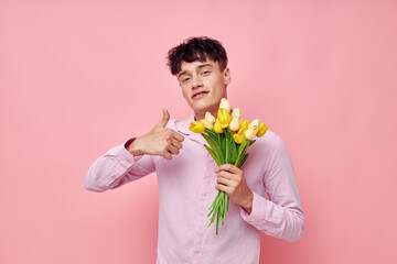 portrait of a young man in a pink shirt with a bouquet of flowers gesturing with his hands model studio