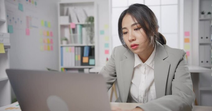 Young Asian businesswoman sit on desk with laptop overworked tired burnout syndrome at office. Exhausted lady with sleeply eye at workplace, Girl not enjoy unhappy with work, Work mental health.