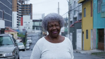 A happy senior black woman standing in a south american street looking at camera