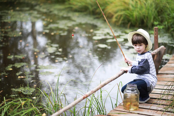 A child is fishing in the autumn morning. Autumn sunset on the pond. A fisherman with a fishing rod on the walkway.