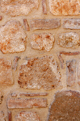 Brown old wall of large and small bricks inside of mortar. Vertical photo.
