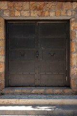 Old wrought iron door in stone wall. Vertical photo.