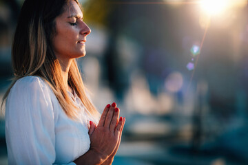 Sunset Meditation. Woman Meditating by the Lake in Prayer Position.