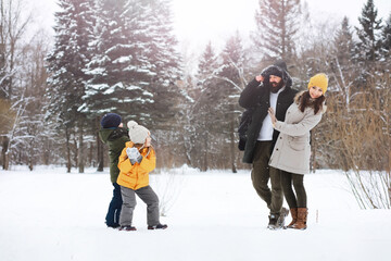 Happy family playing and laughing in winter outdoors in the snow. City park winter day.