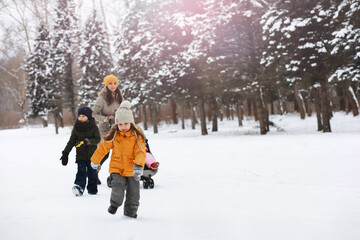 Happy family playing and laughing in winter outdoors in the snow. City park winter day.