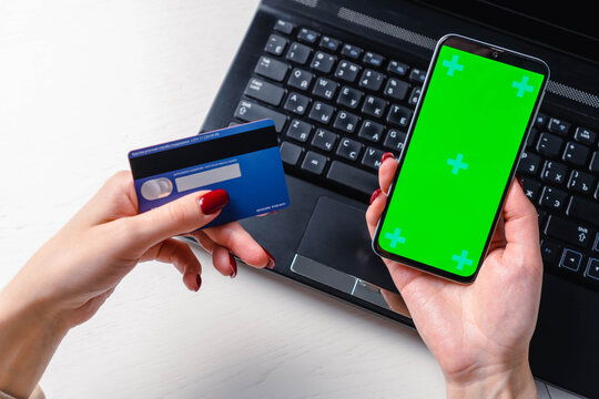 Close up image of woman hands using smartphone blank green screen mockup and holding credit card