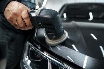 Obraz na płótnie Canvas Car detailing. Male hands with orbital polisher in auto repair shop