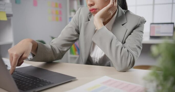 Young Asian businesswoman sit on desk with laptop overworked tired burnout syndrome at office. Exhausted lady with sleeply eye at workplace, Girl not enjoy unhappy with work, Work mental health.