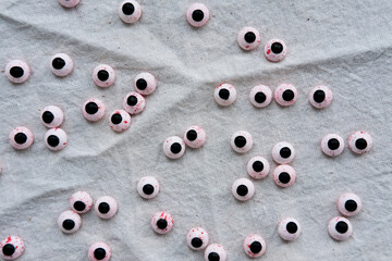 Lots of round plastic doll eyes on a gray background. Flat lay.