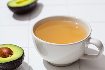 Avocado seed tea in white mug, white background. Vegan trend.