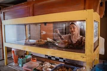 woman with hijab working in her tradtional food shop