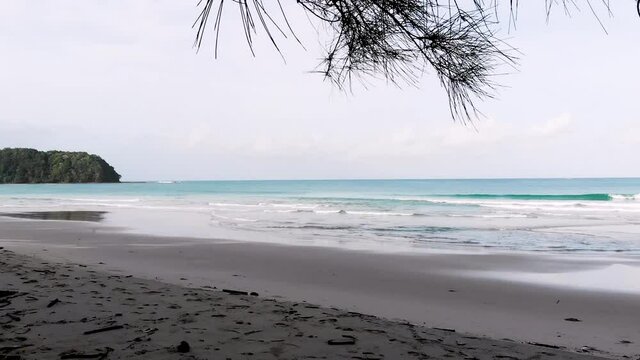 Forward Flying Aerial Drone Shot At Bavang Jamal Beach, Next To The Tip Of Borneo. Flying In between Trees Revealing The Waves Hitting The Sand. Kudat, Malaysian Borneo