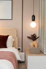Modern bedroom room with stylish comfortable red, brown and yellow pillow on it. Side table lamp.