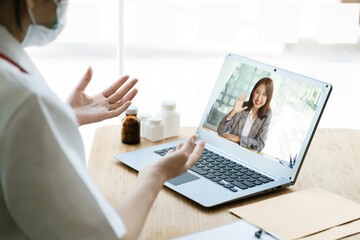 Asian female doctor using laptop computer online video call remote talking to patient, prescribe medicine. Tele medical, telehealth, hospital clinic health care service, or internet technology concept