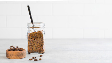 A glass jar with instant coffee and a teaspoon. Copy space.