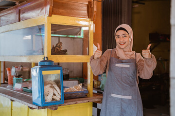 proud muslim woman with her small food stall thumb up