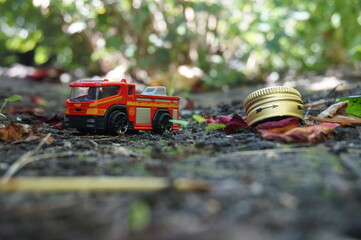 A toy children's fire truck without a ladder. Close-up, shooting on the street, on the ground. Next to the aluminum bottle cap.