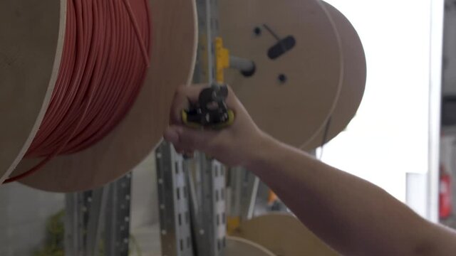 Cutting electric red wire from a spool used for solar panel installation with a cutting tool, Slow motion close up shot