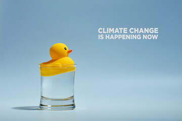 Yellow toy rubber duck floating in a glass of water. Global warming and water resources