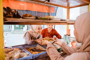 muslim couple sitting on traditional food stall, waiting for iftar time