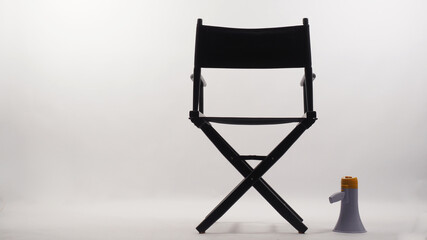 Back of Black director chair and megaphone on white background.