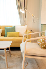 Modern living room interior with stylish comfortable yellow sofa and green and white pillow on it.