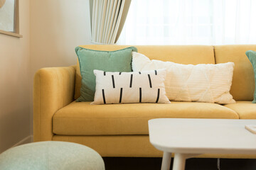 Modern living room interior with stylish comfortable yellow sofa and green and white pillow on it.