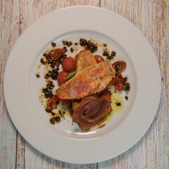 Fish recipe, Fillet of red mullet, crushed cherry tomatoes and olives. High quality photo
