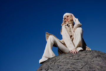 Fototapeta premium young woman sitting on a stone nature blue sky in a hat lifestyle