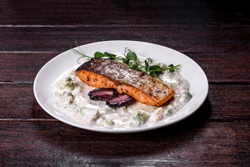Tasty baked salmon fish on a white dish with broccoli and pea sprouts