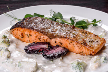 Tasty baked salmon fish on a white dish with broccoli and pea sprouts