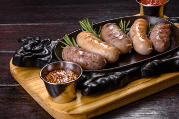 Delicious fresh juicy sausages grill with red sauce in a beautiful cast iron pan