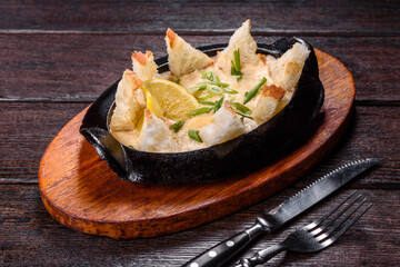 A delicious seafood dish baked with cheese and breadcrumbs in a cast iron bowl