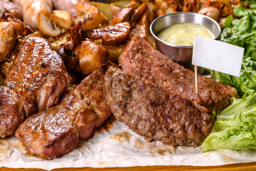 Several types of roasted meat with spices and herbs on a wooden tray