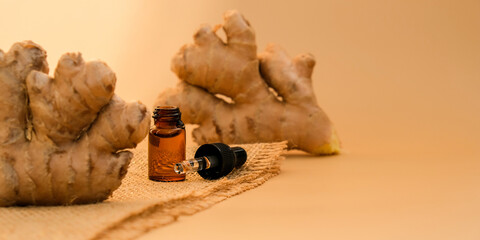 Glass pipette of essential ginger oil, ginger root on beige background. Aromatherapy, spa and...