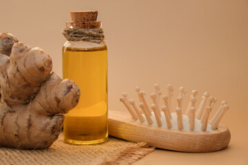Glass bottle of essential ginger oil, ginger root on beige background. Healthy alternative living....