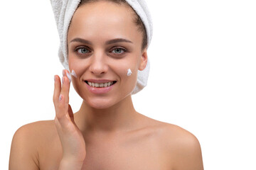 young woman after a shower applies cream on her face