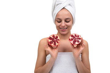 young woman after spa treatments holding a cut pomegranate in her hands on a white background